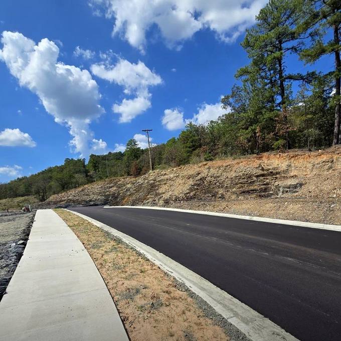 Freshly Paved Street Curve and Concrete Sidewalk Under Bright Blue Sky