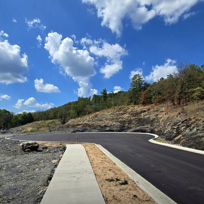 Paved Hillside Street and Concrete Sidewalk Beside Exposed Bluff Strata